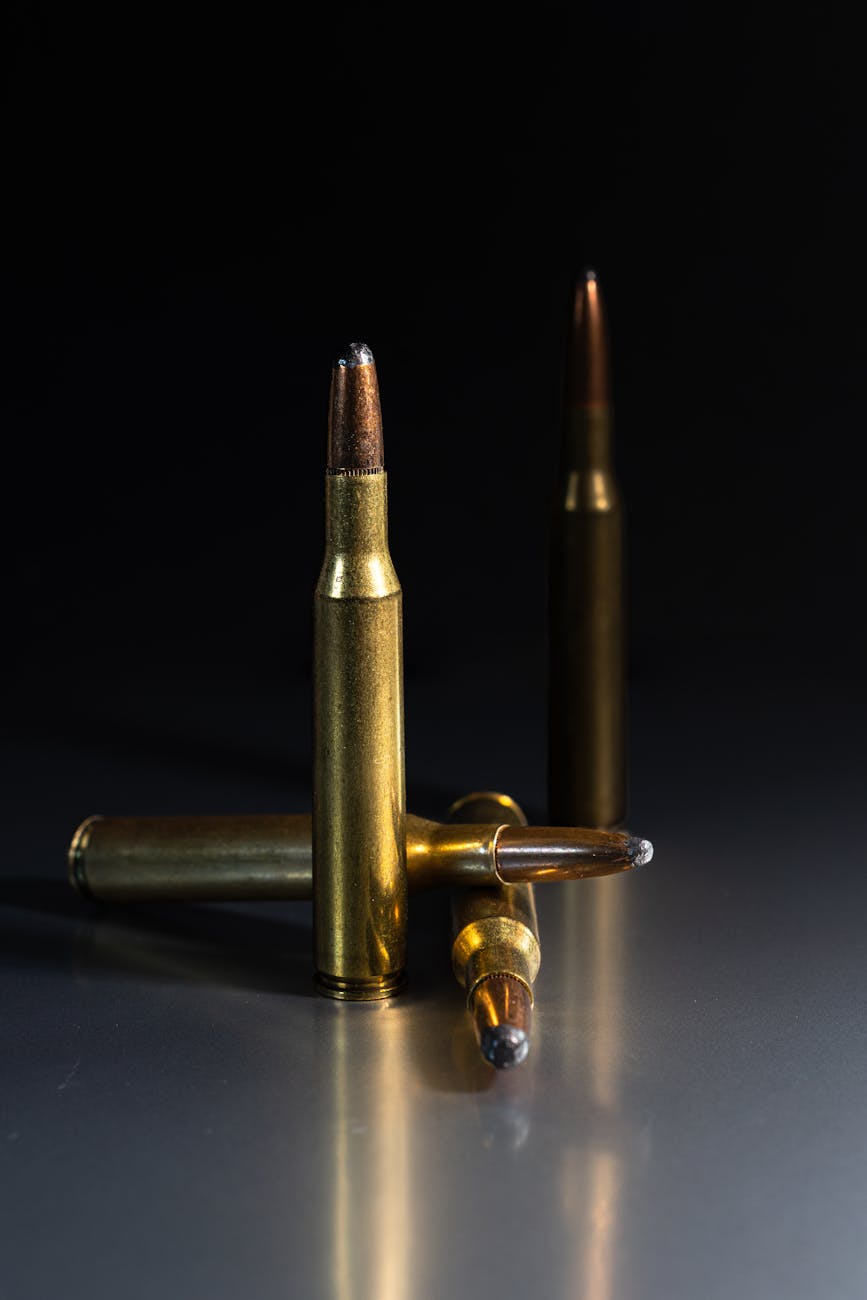 Ampuma-aseisiin liittyvät palvelut Detailed shot of rifle bullets standing on a reflective surface, showcasing metallic textures.